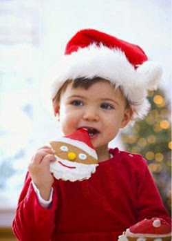 Toddler in a Santa hat holding a Santa-face cookie