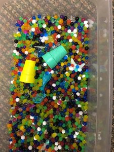 Plastic bin of colorful water beads with plastic cups