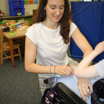 Therapist in a white shirt working with a child's arm in a therapy room