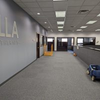 Long hallway with the LLA Therapy logo on the wall and a toy car at the end