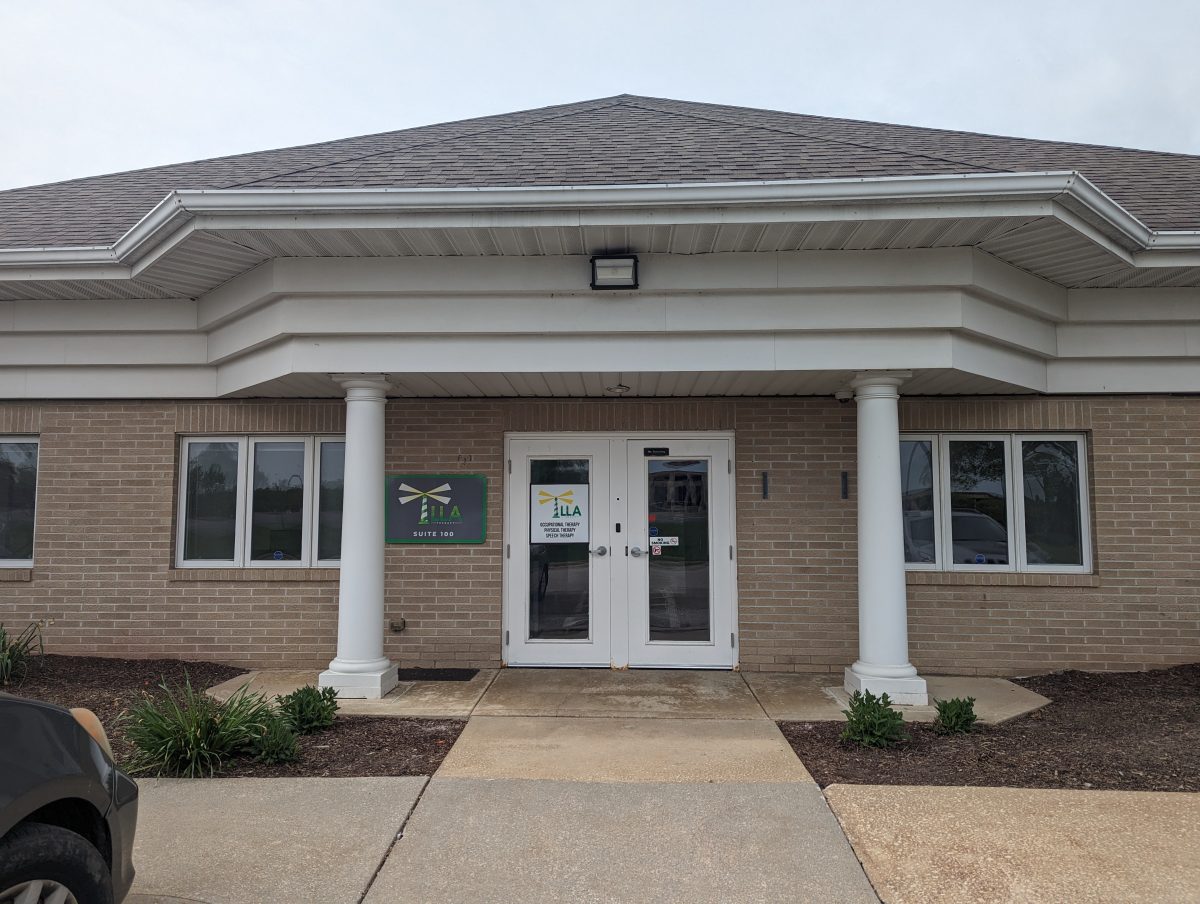 Entrance to a brick LLA Therapy office with white columns and double glass doors