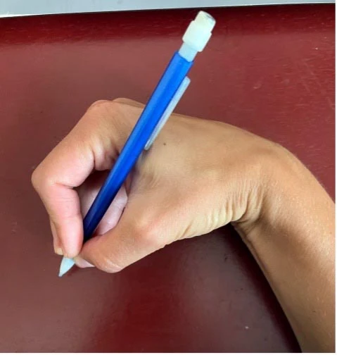 Hand holding a blue pencil with the wrist bent downward in a hooked grasp