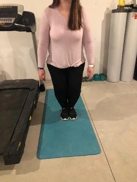 Person standing with feet together on a teal mat, ready to demonstrate a bunny hop