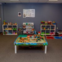 Playroom with a wooden train table, shelves of toys and a toy kitchen