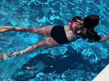 Girl swimming underwater along the surface of a pool