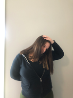 Woman turning her head down and to the side with a hand on her head to demonstrate a levator stretch
