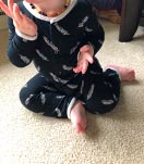 Baby sitting on a carpet in a side-sitting position