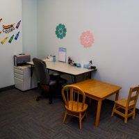 Small therapy office with a desk, rolling chair and a wooden child's table and chairs